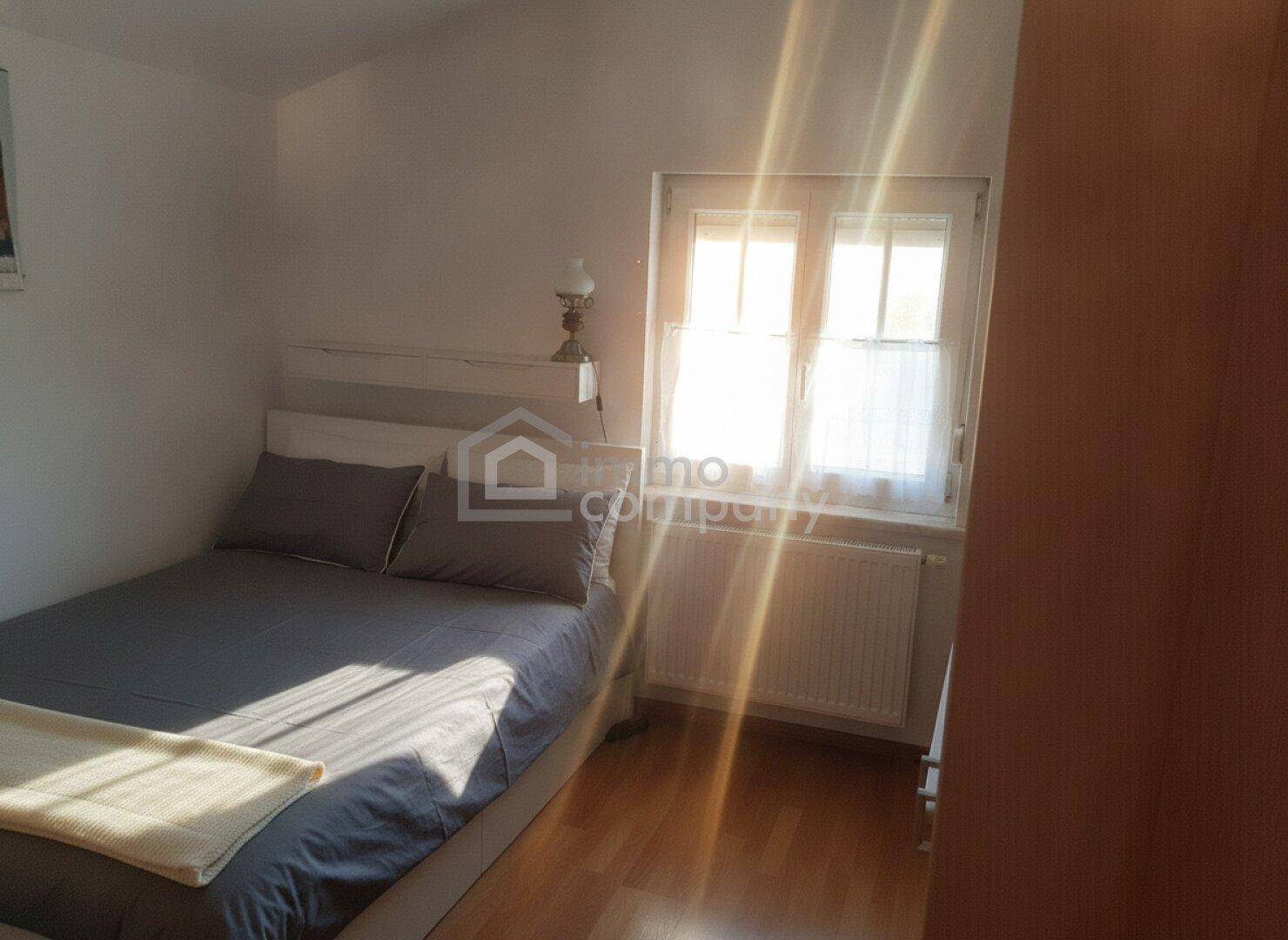 Helles Schlafzimmer mit Einzelbett und Fenster, durchflutet von natürlichem Sonnenlicht.