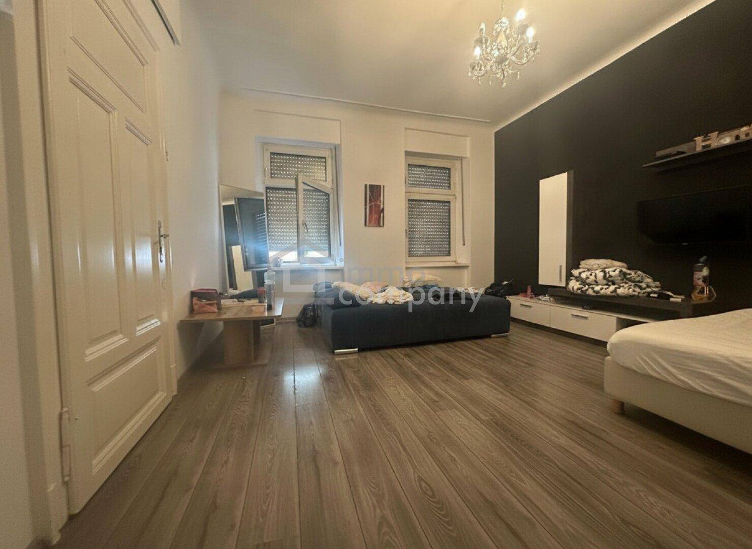 Wohnbereich mit Holzboden, dunkler Wand und einem Bett, das den Raum vielseitig nutzbar macht.