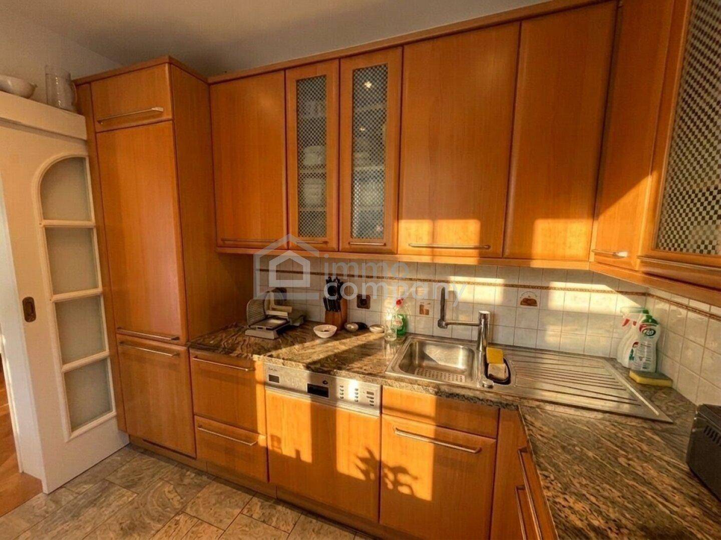 Funktionale Küche mit Spülbecken, Geschirrspüler und weiteren Holzschränken für Stauraum.