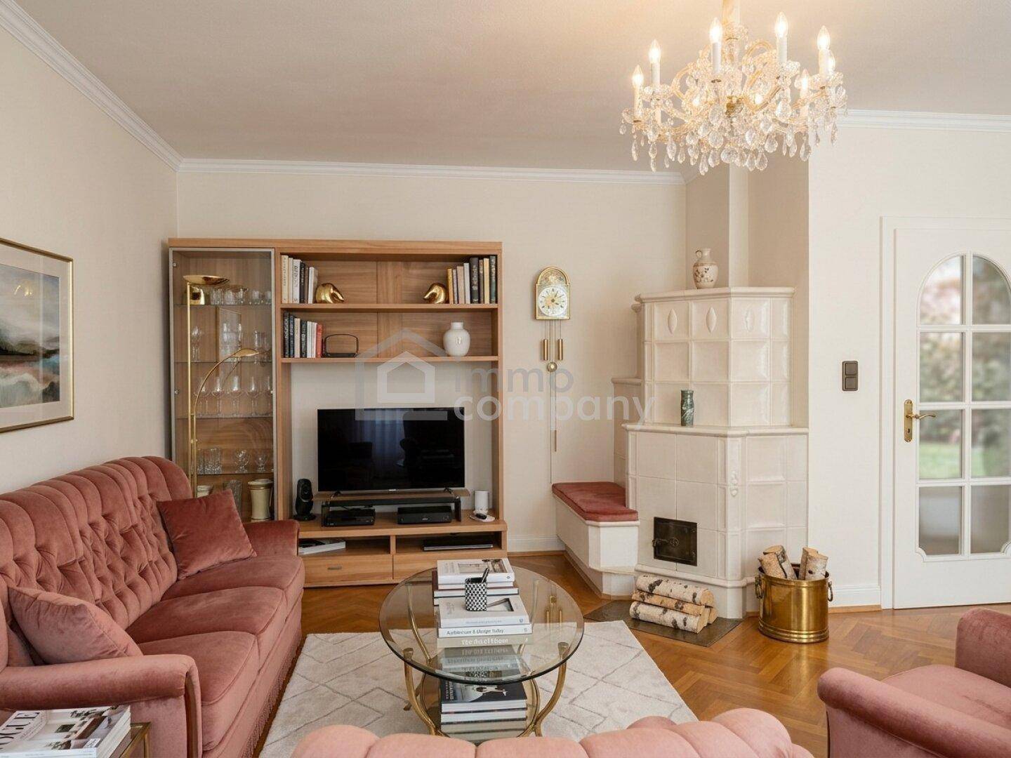 Gemütliches Wohnzimmer mit Kachelofen, elegantem Kronleuchter und Parkettboden.