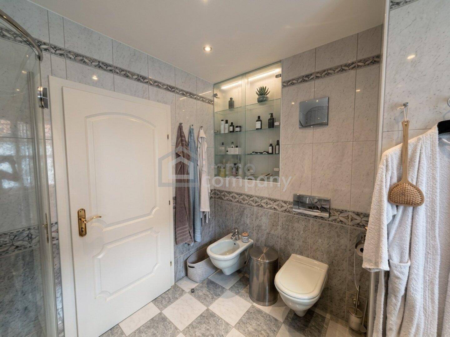 Badezimmer mit Toilette, Bidet und einem praktischen Einbauschrank für Badutensilien.