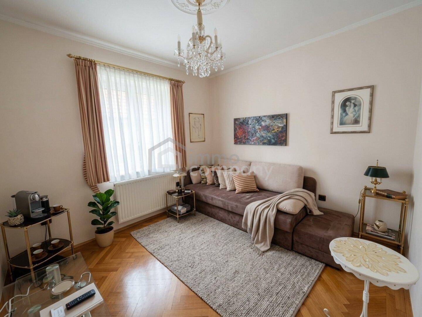 Gemütlicher Wohnbereich mit bequemer Couch, Parkettboden und einem Fenster mit Vorhängen.