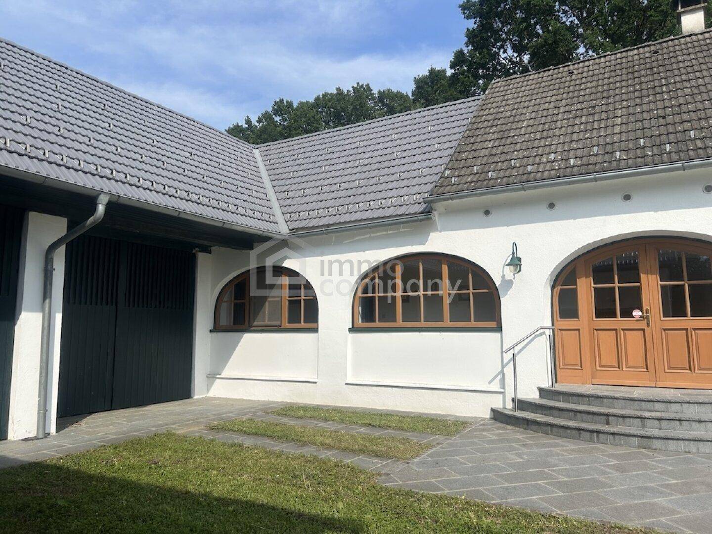 Eingangsbereich des Hauses mit Steintreppe, Holztür und angrenzender Garage.
