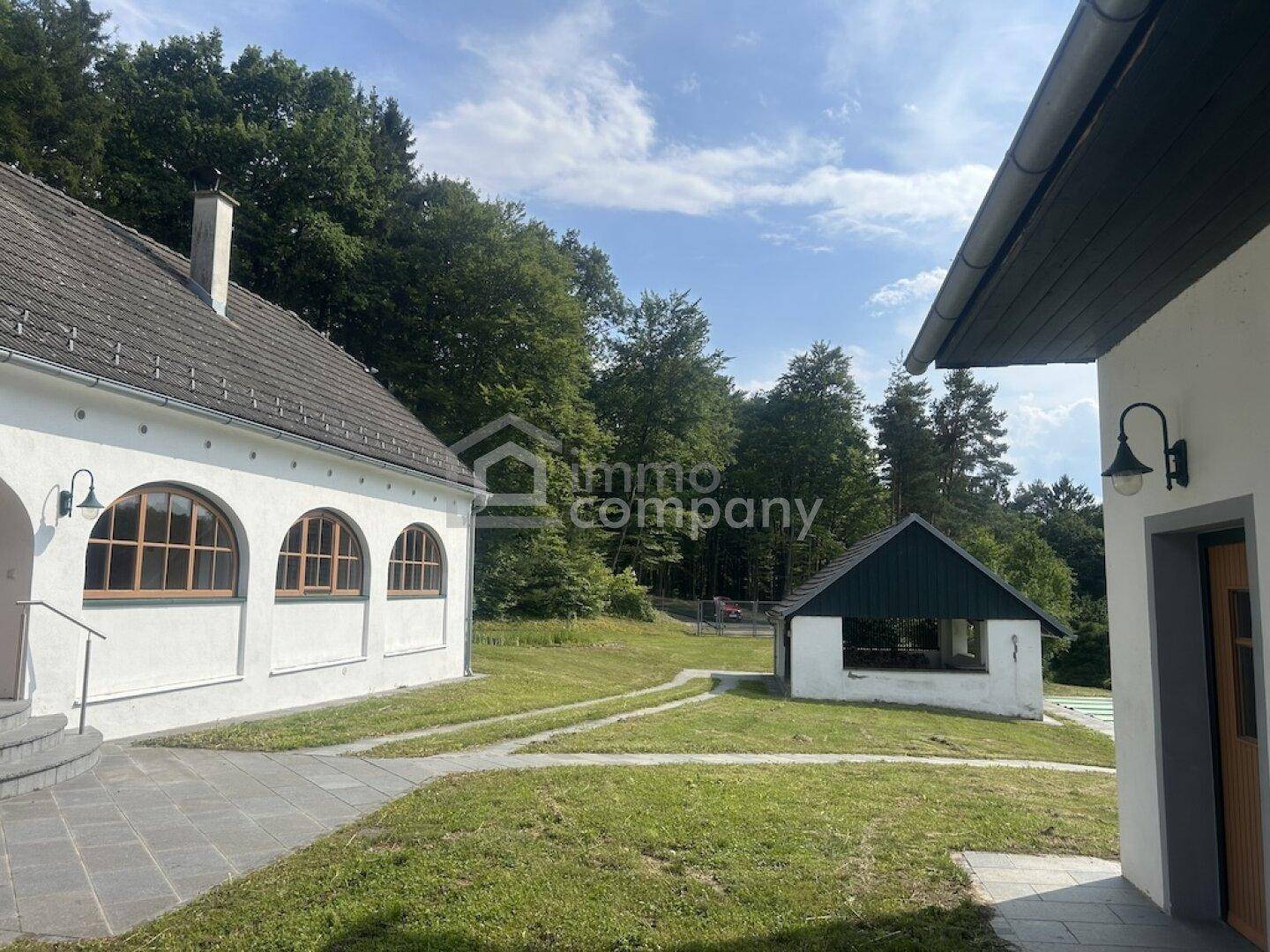Weitläufiger Gartenbereich mit einem kleinen Gartenhaus und Blick auf den umliegenden Wald.