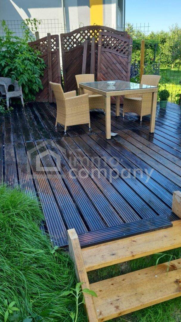 Sonnige Holzterrasse mit Gartenmöbeln und Sichtschutz, ideal für entspannte Stunden im Freien.