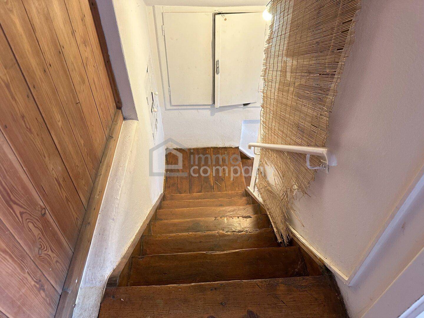 Rustikale Holztreppe führt in den unteren Bereich des Hauses, mit einfacher Wandgestaltung.