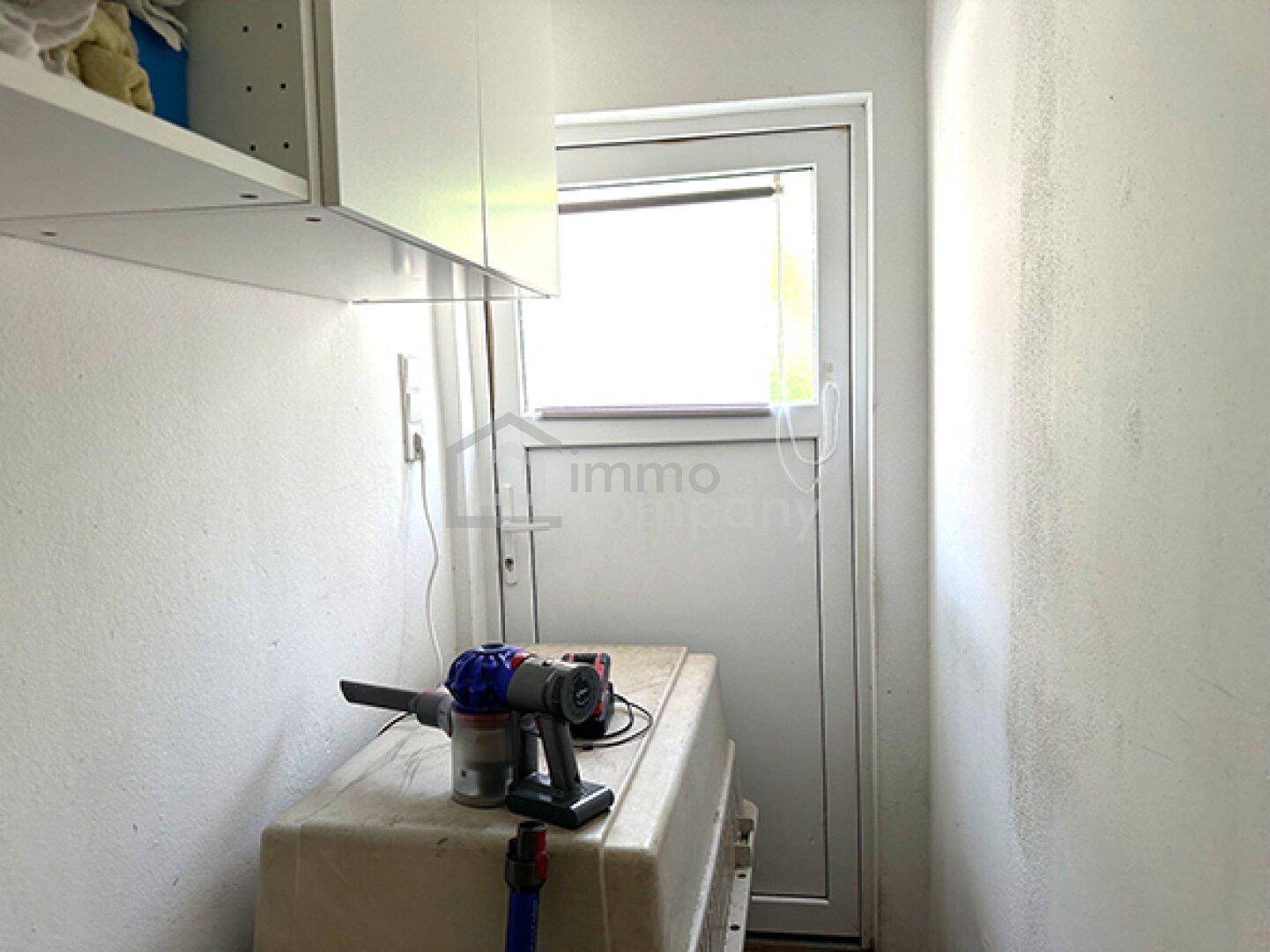 Kleiner Abstellraum mit Fenster und Regalen, ideal für Haushaltsgeräte und Lagerung.
