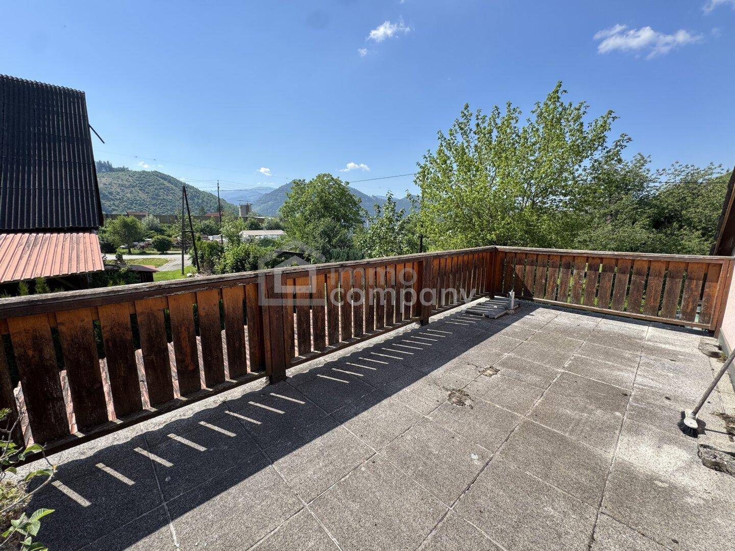 Große gepflasterte Terrasse mit Holzzaun und weitem Blick auf die umliegende Berglandschaft.