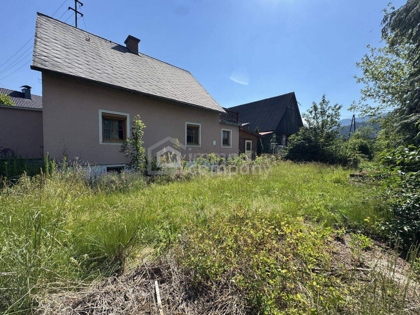 Rückansicht eines Hauses mit Satteldach und einem großen, naturbelassenen Gartenbereich.