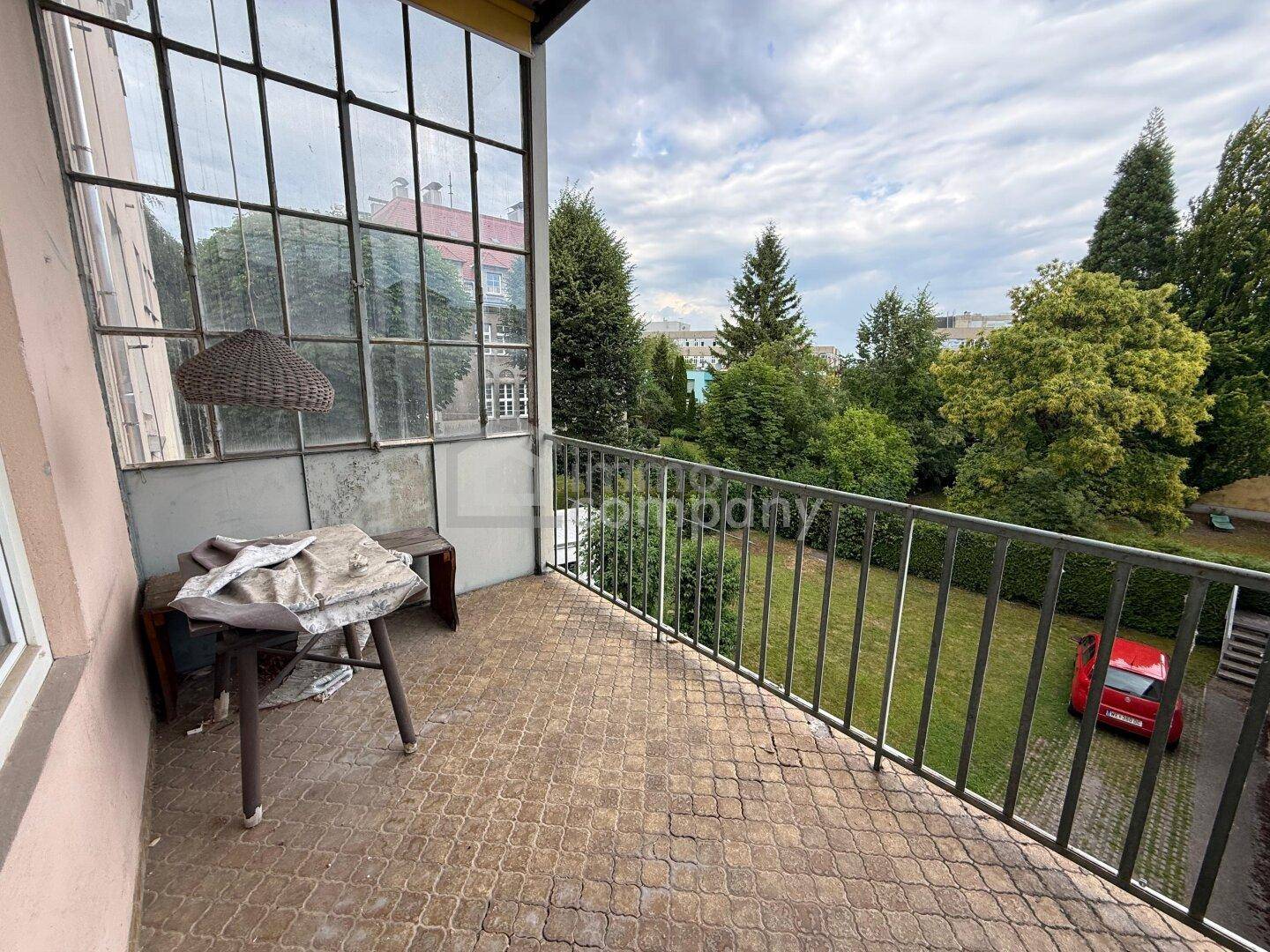 Balkon mit Fliesenboden, Metallgeländer und Blick ins Grüne.