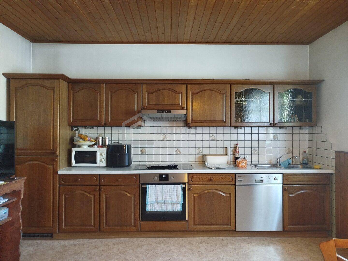 Traditionelle Holzküche mit Einbauschränken, weißen Fliesen und integrierten Geräten.