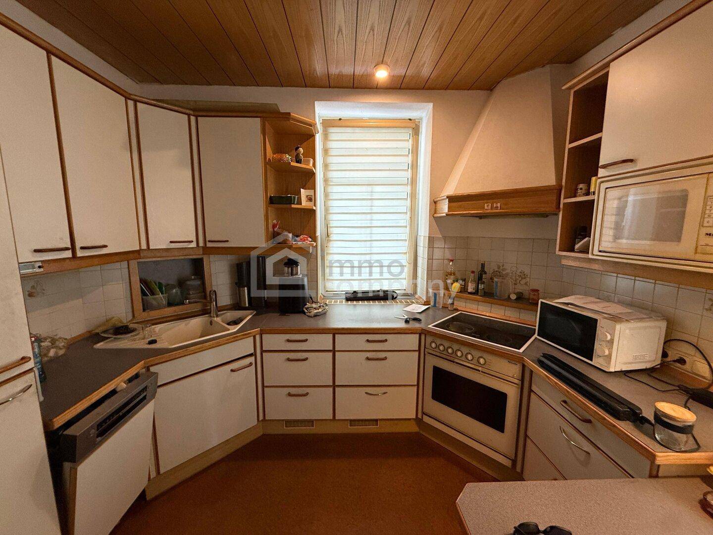 Küche mit weißen Einbauschränken, Holzdecke und integrierten Geräten, inklusive Fenster.