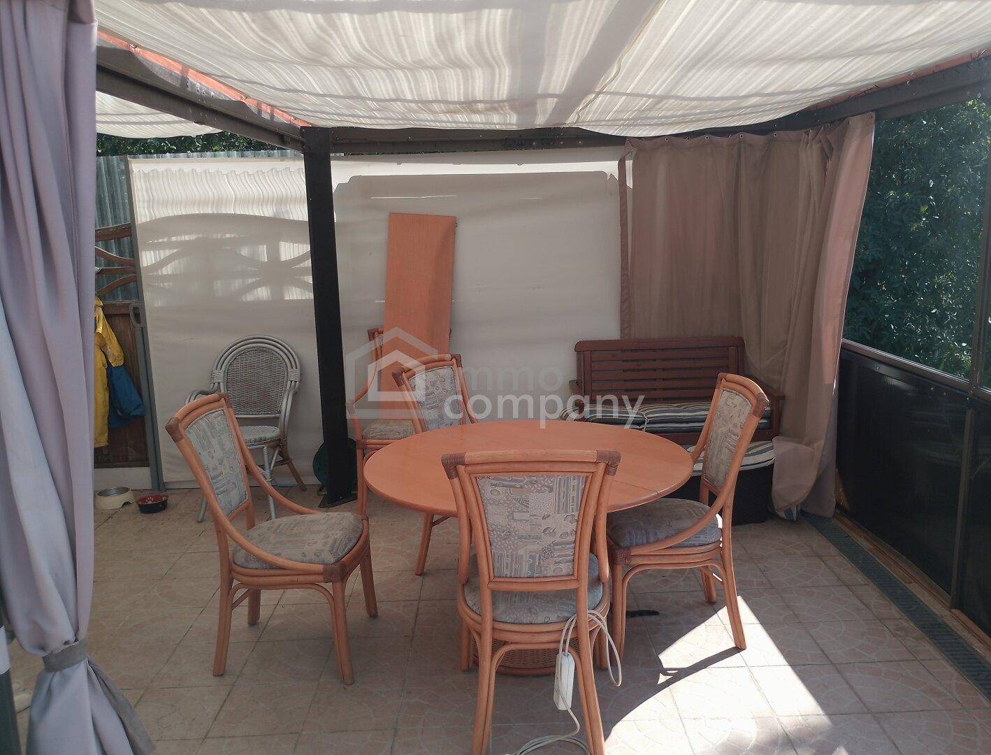 Überdachte Terrasse mit Esstisch und Stühlen, ideal für Mahlzeiten im Freien.