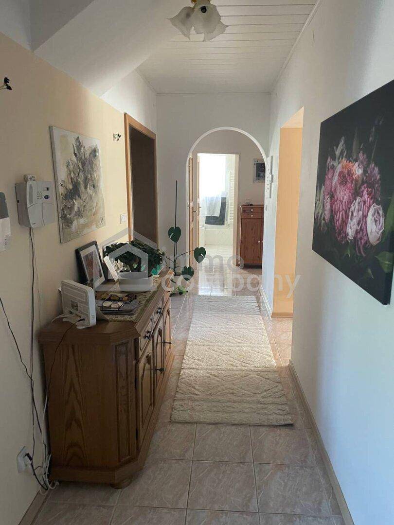 Heller Flur mit Fliesenboden, Holzkredenz und einem Durchgang zu weiteren Räumen.