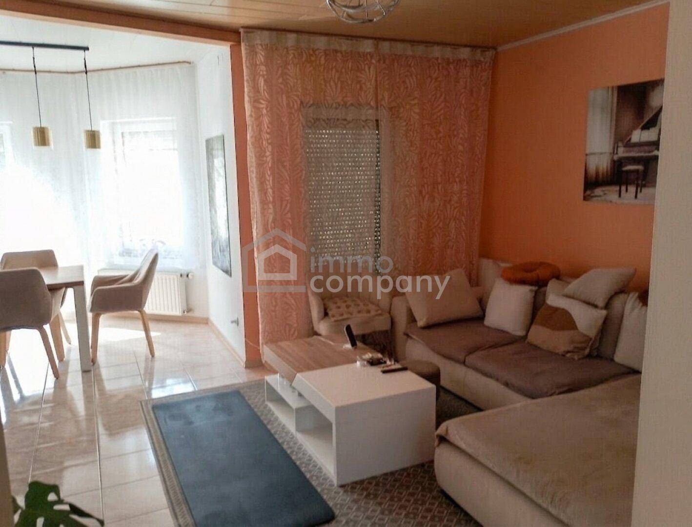 Gemütliches Wohnzimmer mit Sofa, Couchtisch und Zugang zum Essbereich.