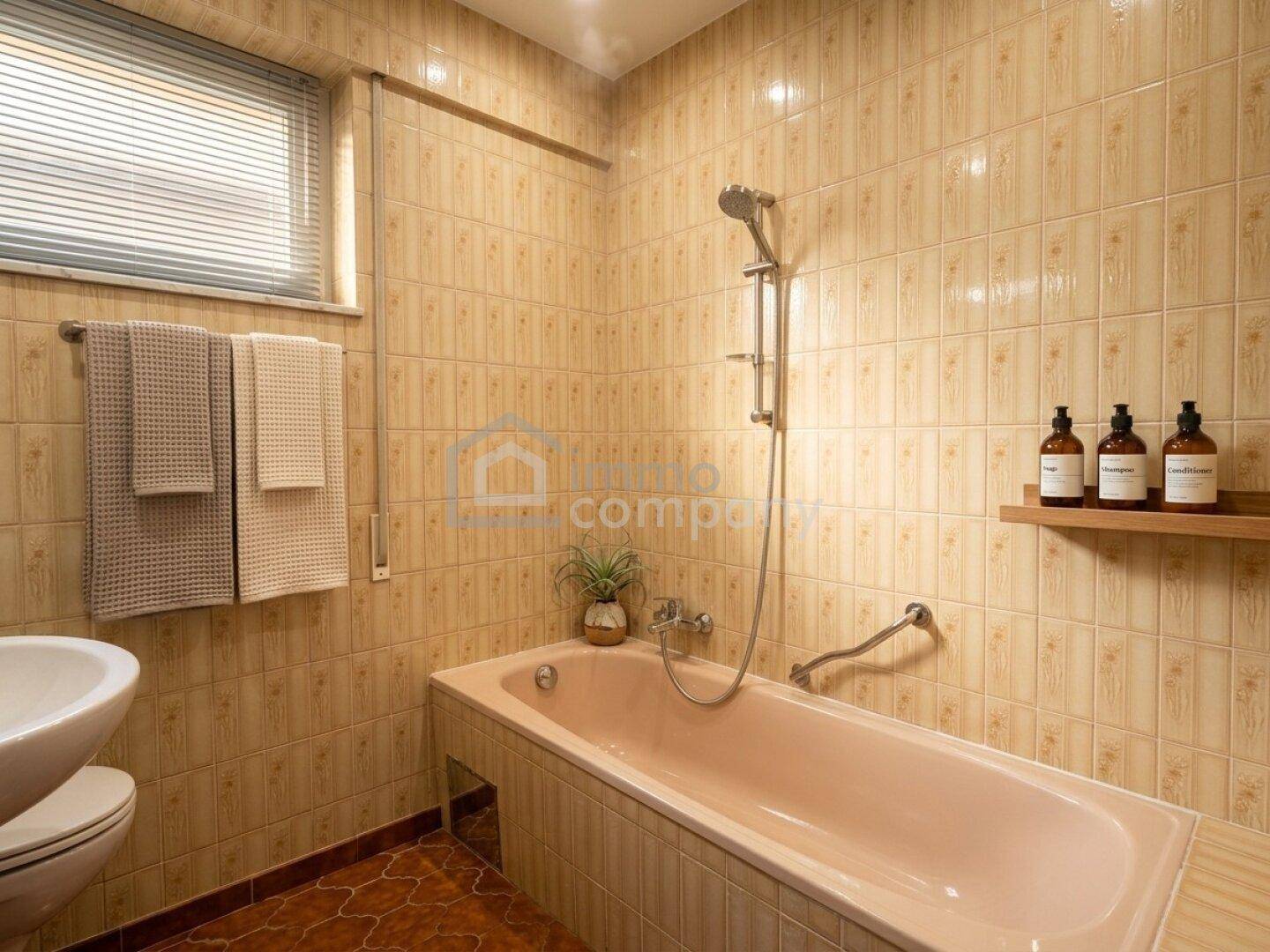 Badezimmer mit beigefarbenen Fliesen, einer Badewanne und einem Fenster für Tageslicht.