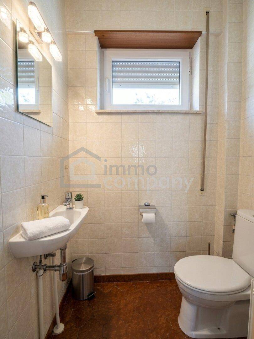 Kleines Gäste-WC mit Fliesen an den Wänden, Waschbecken und Fenster.