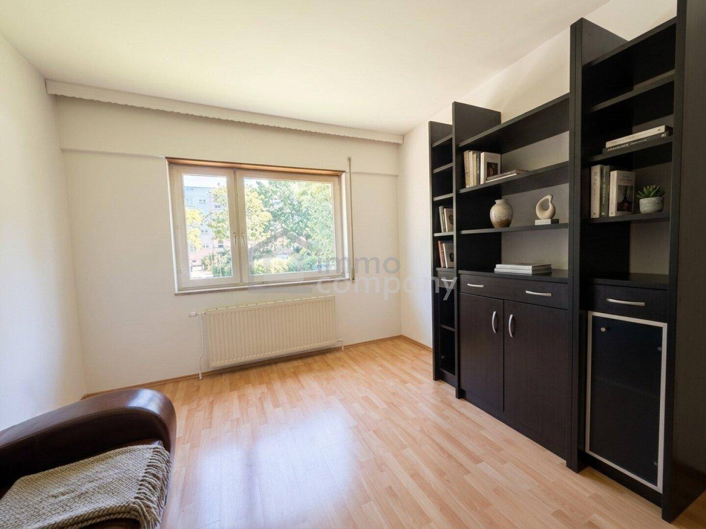 Helles Arbeitszimmer mit Parkettboden, Bücherregal und großem Fenster mit Blick ins Grüne.