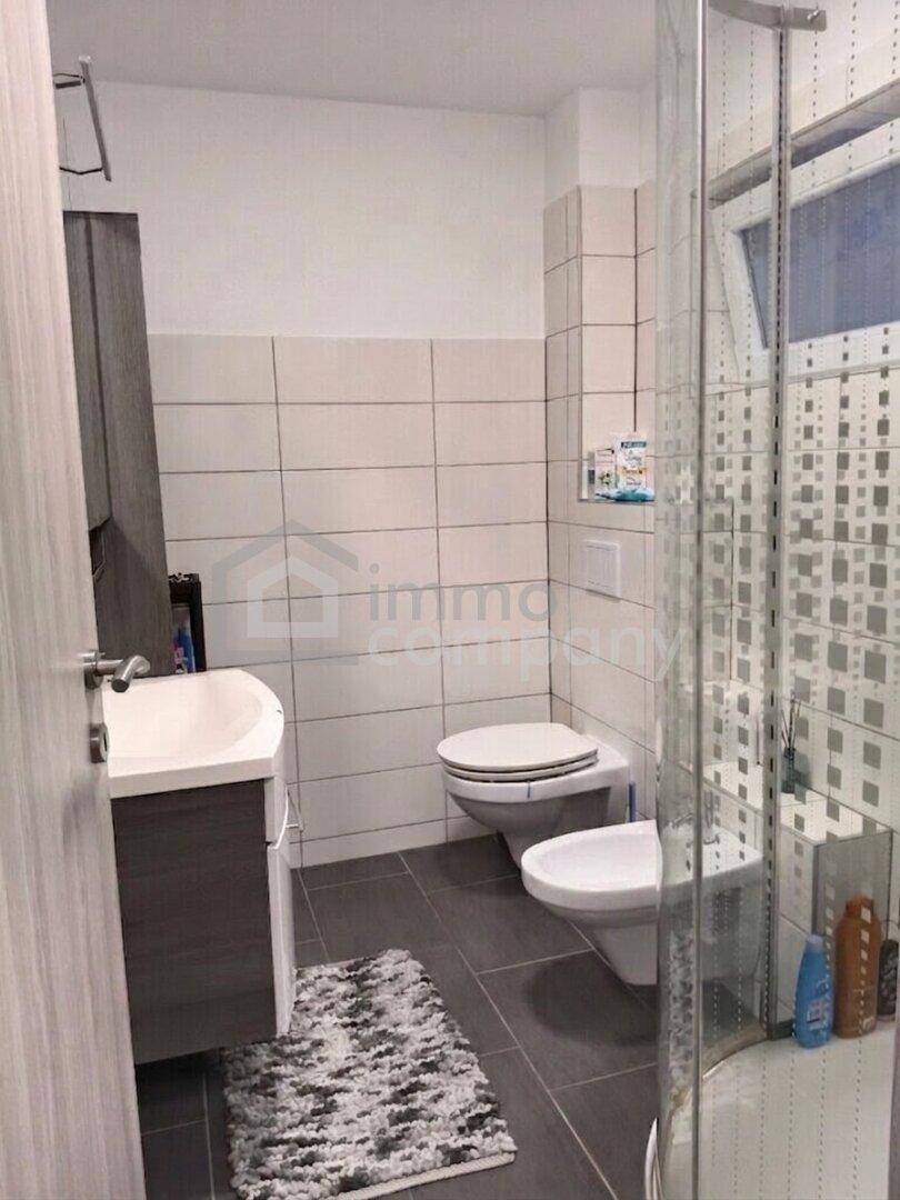 Modernes Badezimmer mit Waschbecken, Toilette, Bidet und Duschkabine.