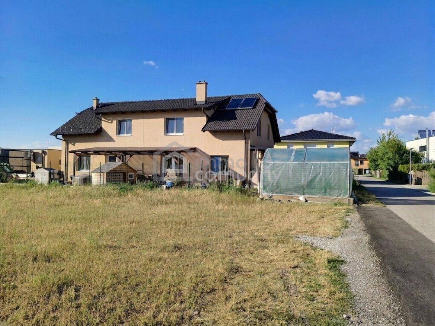 Rückansicht des Hauses mit großem Gartenbereich, Gewächshaus und Solarpaneelen auf dem Dach.