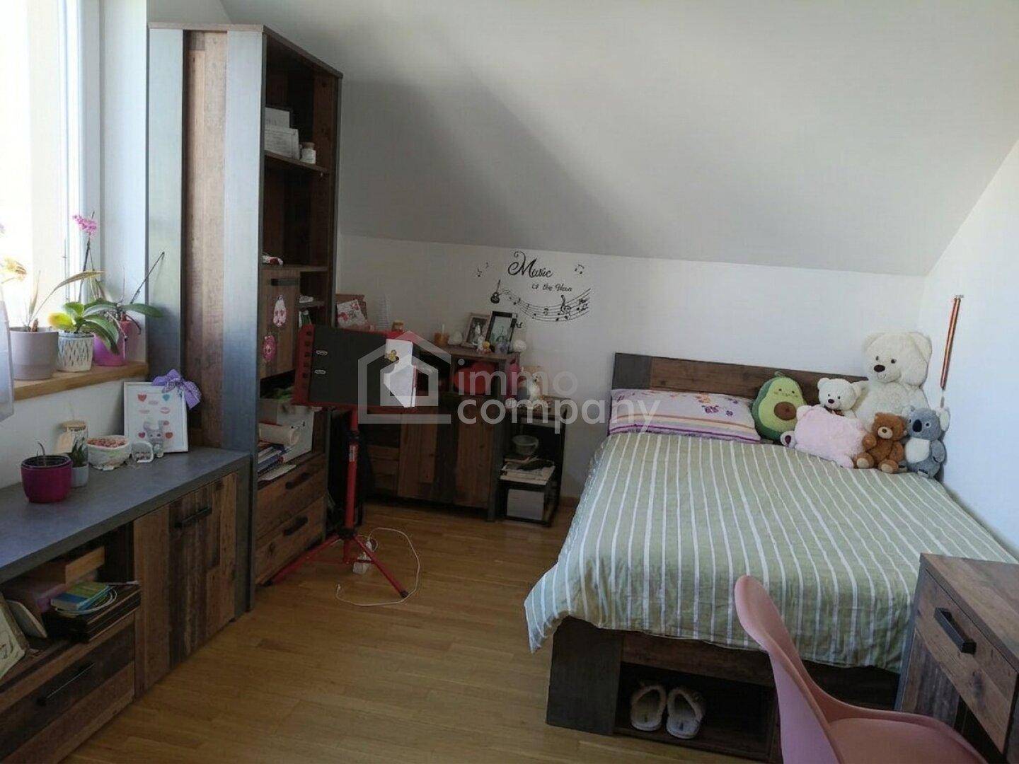 Kinderzimmer oder Gästezimmer mit Einzelbett, Holzmöbeln und Dachschräge.