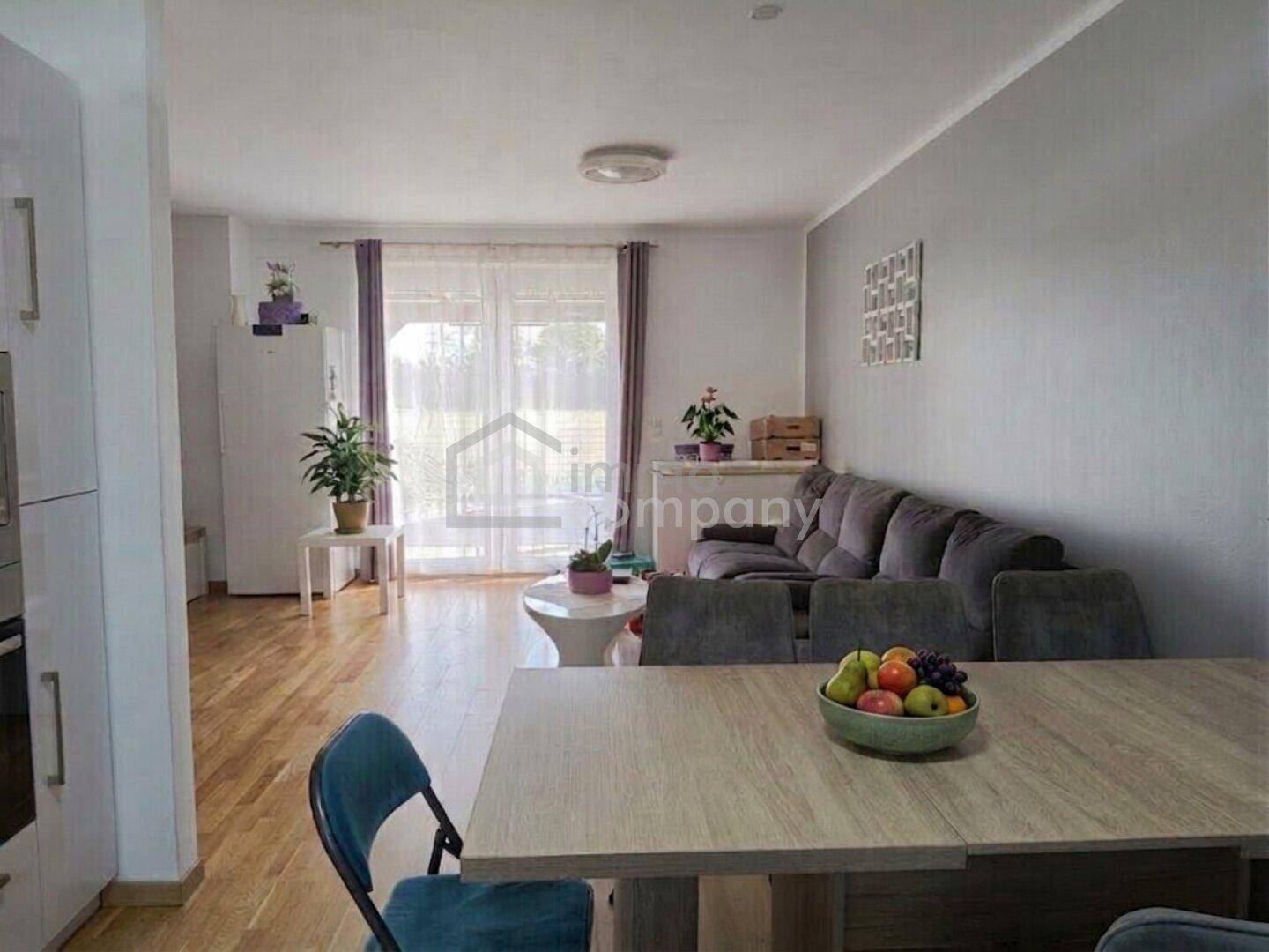Heller offener Wohn-Essbereich mit Holzboden, bequemer Couch und Esstisch.