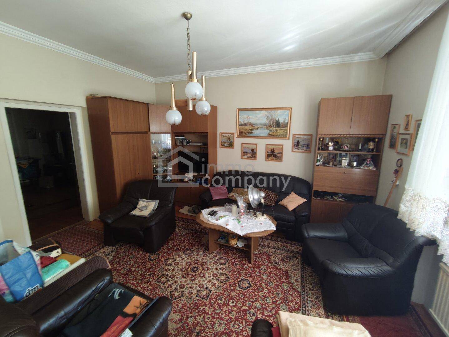 Gemütliches Wohnzimmer mit traditionellen Möbeln, Teppich und Holzschränken, gut erhalten.