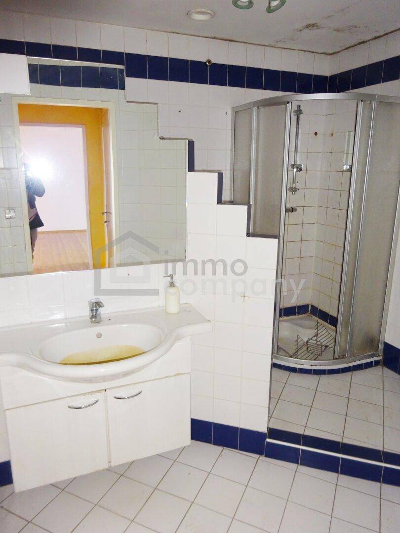 Badezimmer mit Duschkabine, Waschbecken und blauen Akzentfliesen.