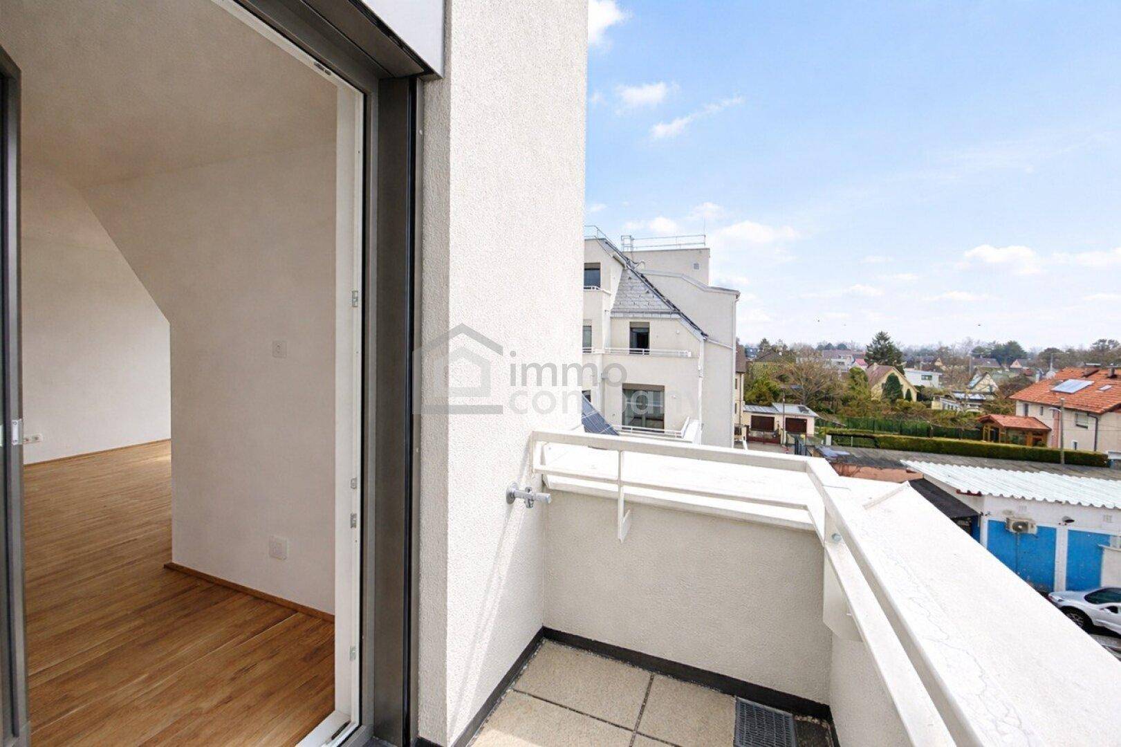 Kleiner Balkon mit weißem Geländer und Blick auf die Umgebung und andere Gebäude.