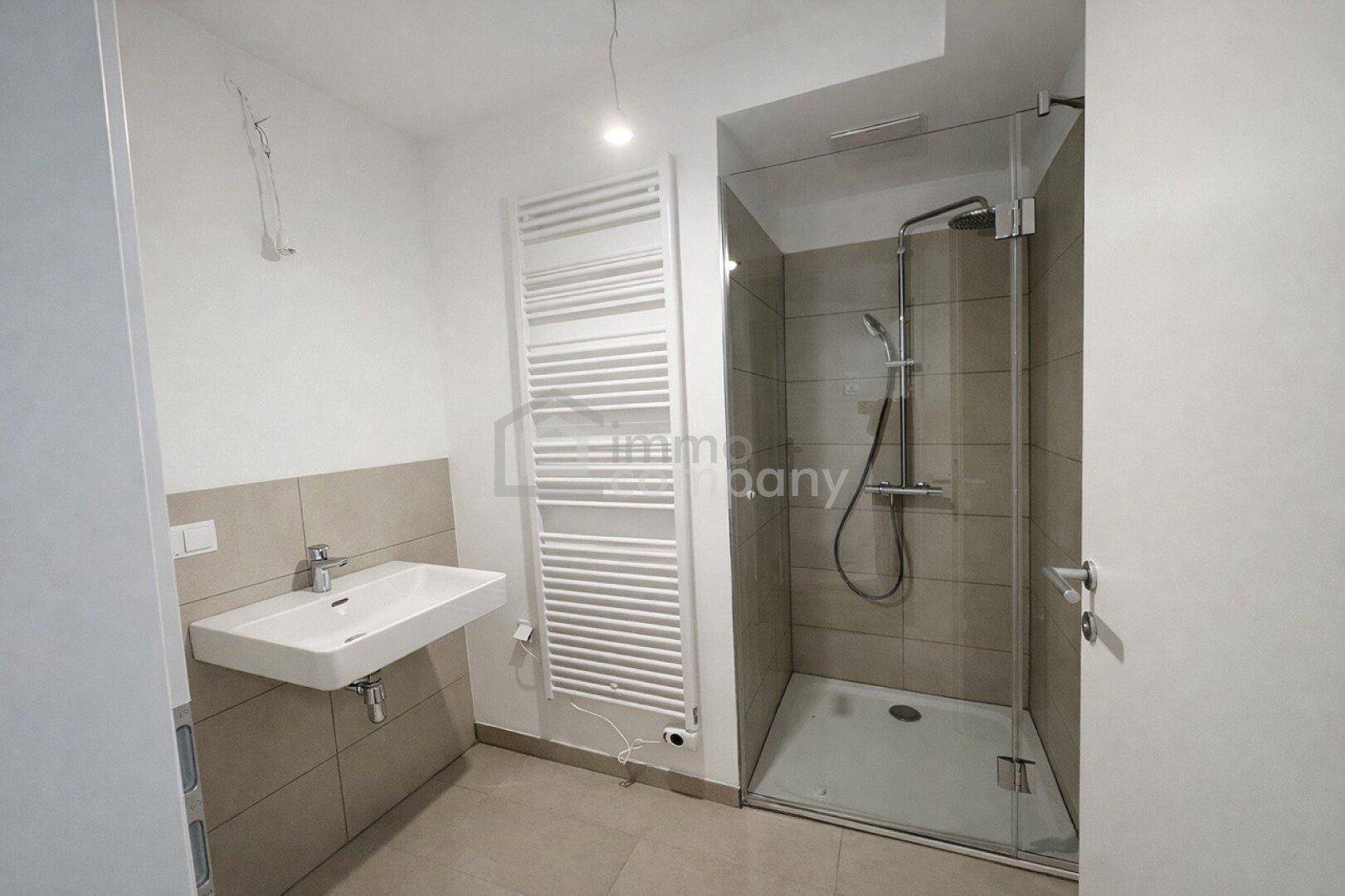 Modernes Badezimmer mit Duschkabine, Waschbecken und beheiztem Handtuchhalter.