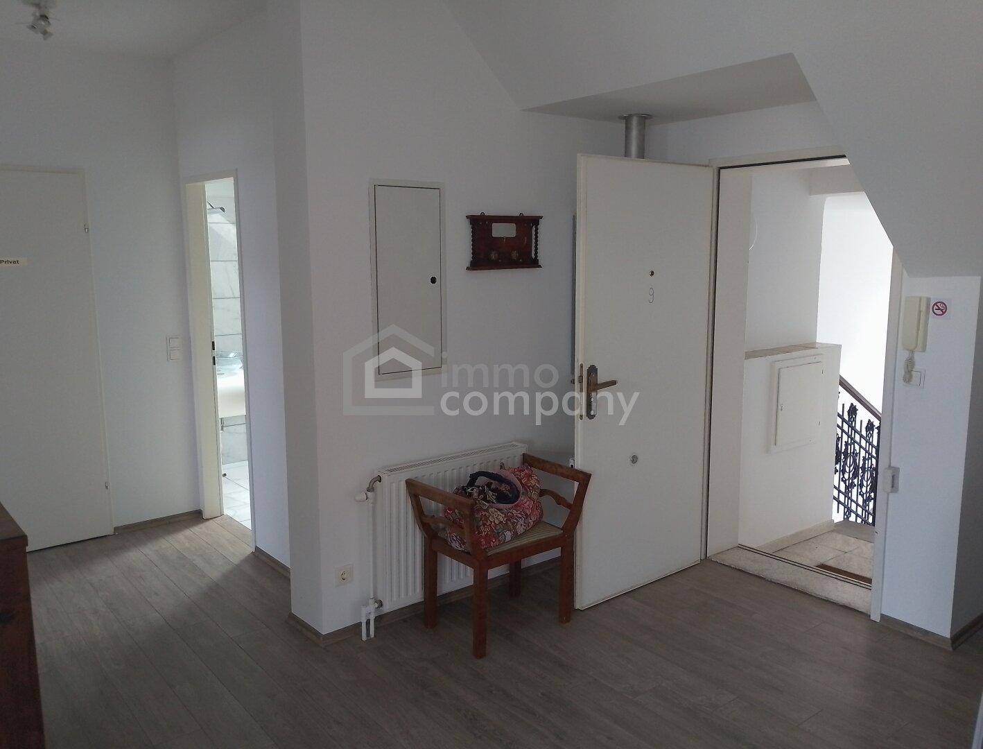 Heller Flur mit Laminatboden, Heizkörper und Zugang zu weiteren Räumen sowie einer Treppe.