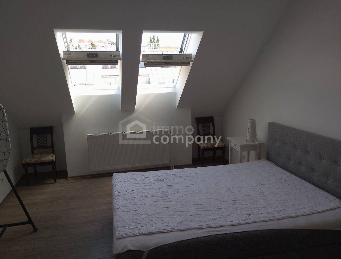 Schlafzimmer im Dachgeschoss mit Doppelbett, Heizkörper und zwei großen Dachfenstern für viel Licht.