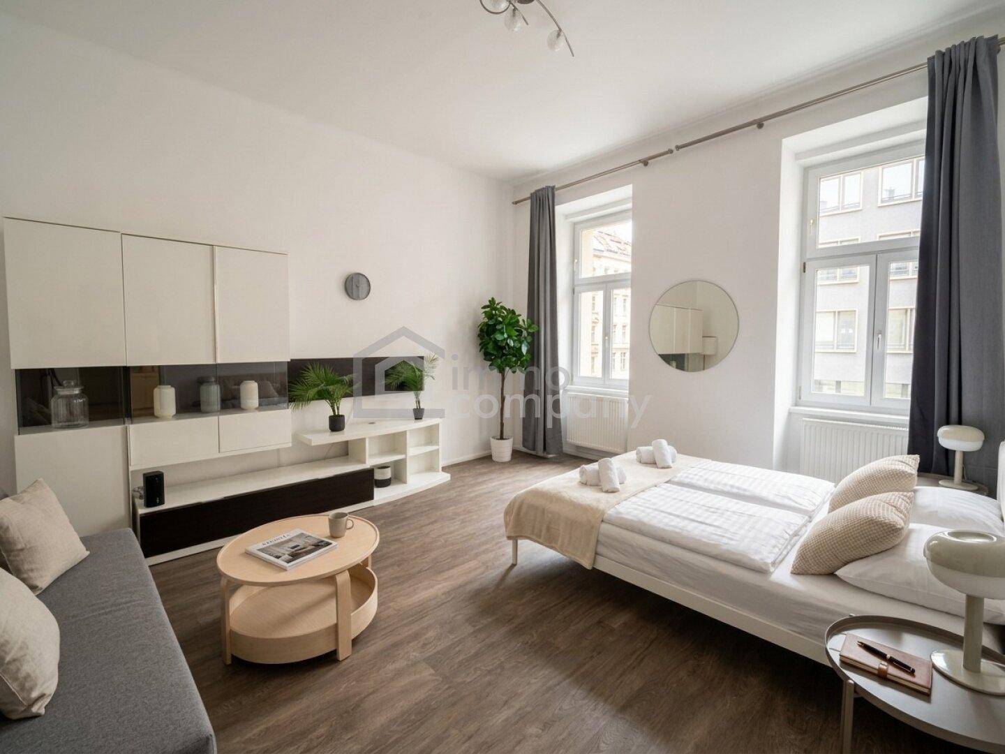 Gemütliches Schlafzimmer mit großzügigen Fenstern, einem Sofa und modernen Wandregalen für Stauraum.