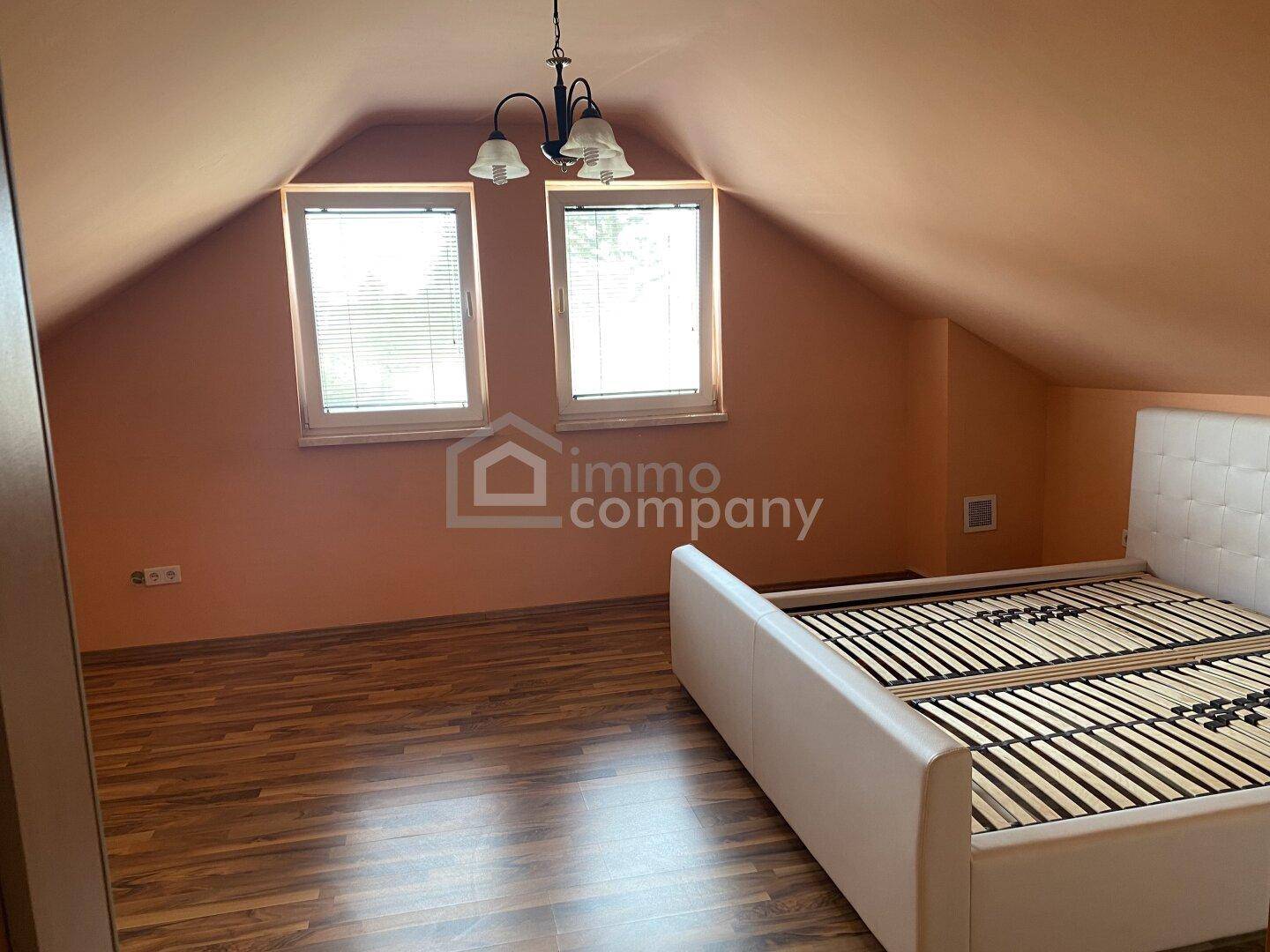 Schlafzimmer im Dachgeschoss mit Dachschrägen, Laminatboden und Doppelbett.