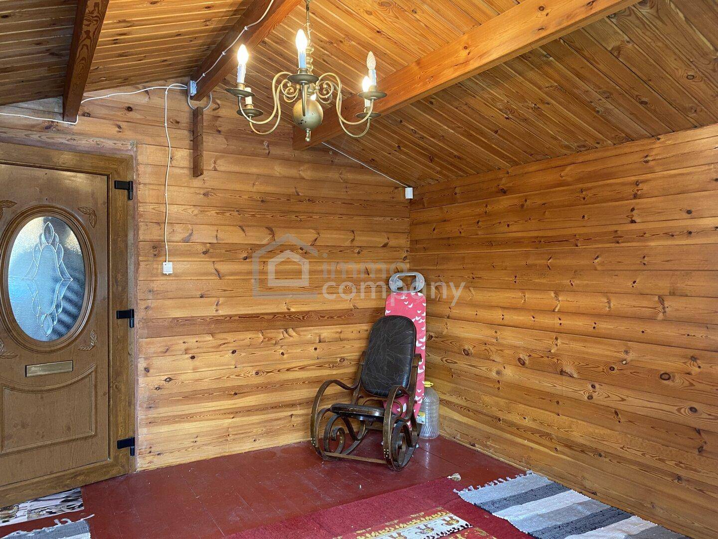Rustikaler Raum mit Holzverkleidung an Wänden und Decke, sowie einem Schaukelstuhl.