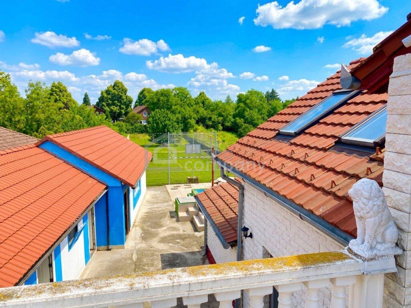 Blick vom Balkon auf das Grundstück mit weiteren Gebäuden und viel Grün.
