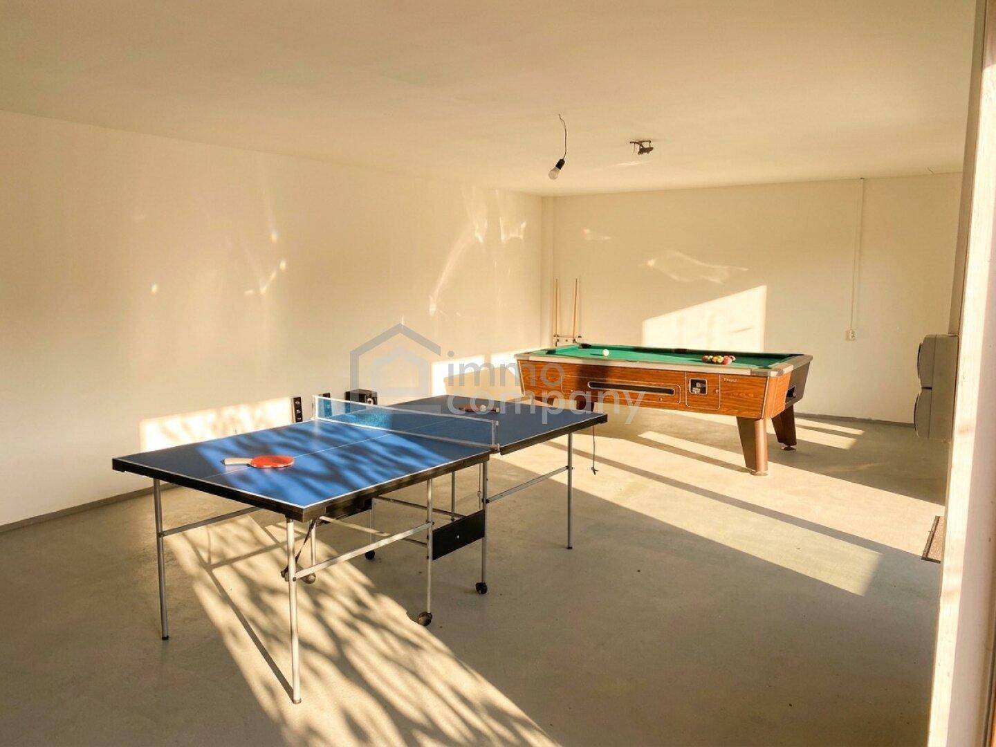 Geräumiger Spielraum mit Tischtennisplatte und Billardtisch, gut beleuchtet.