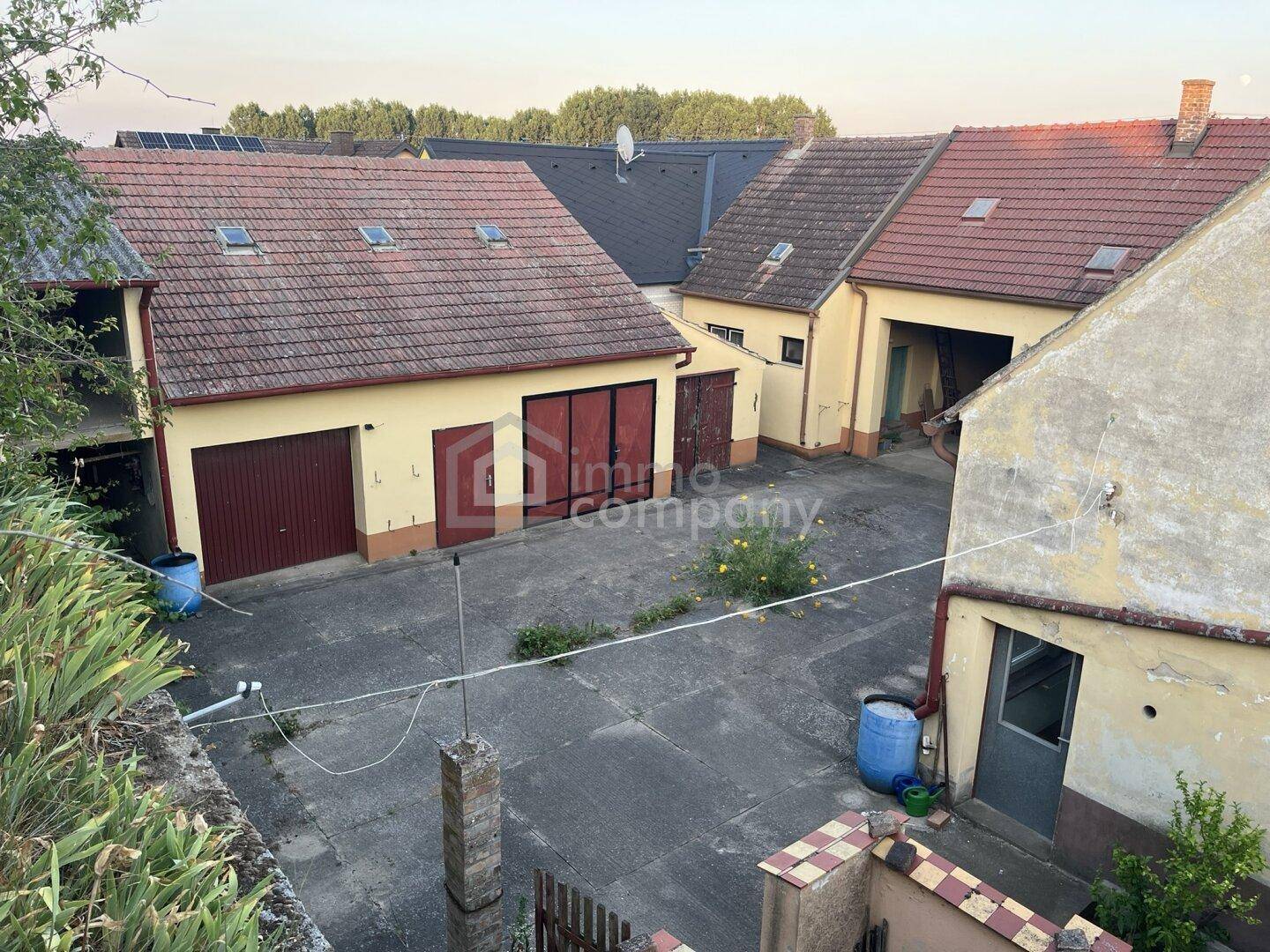 Weitläufiger Innenhof mit mehreren Gebäuden und Garagen, von oben betrachtet.