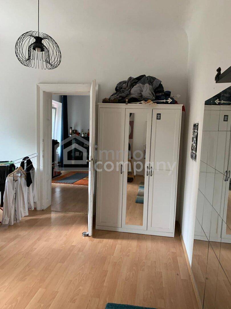 Raum mit Laminatboden und einem weißen Kleiderschrank mit Spiegeltüren.