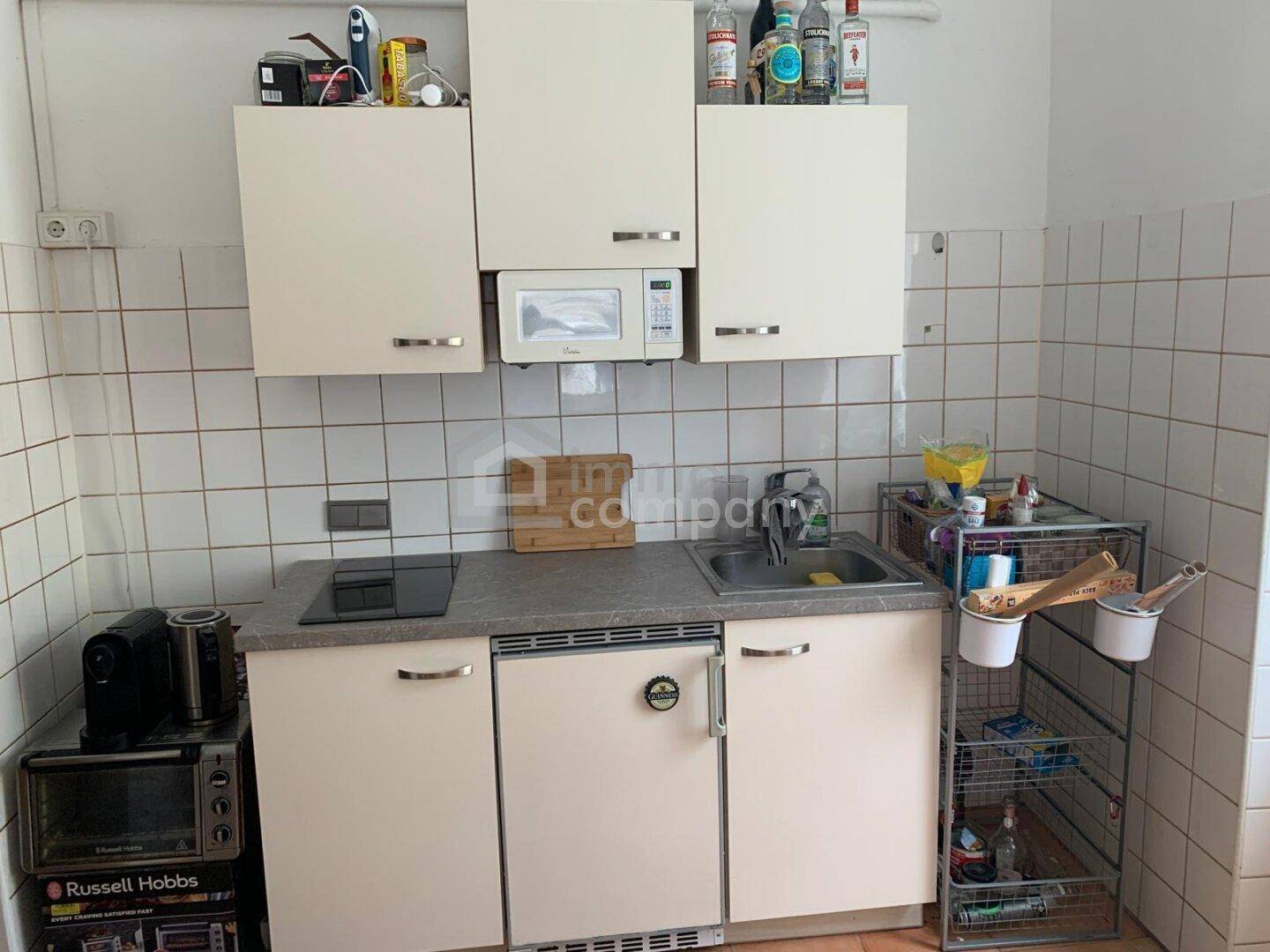 Kleine Küchenzeile mit integrierter Mikrowelle, Kochfeld und Kühlschrank.