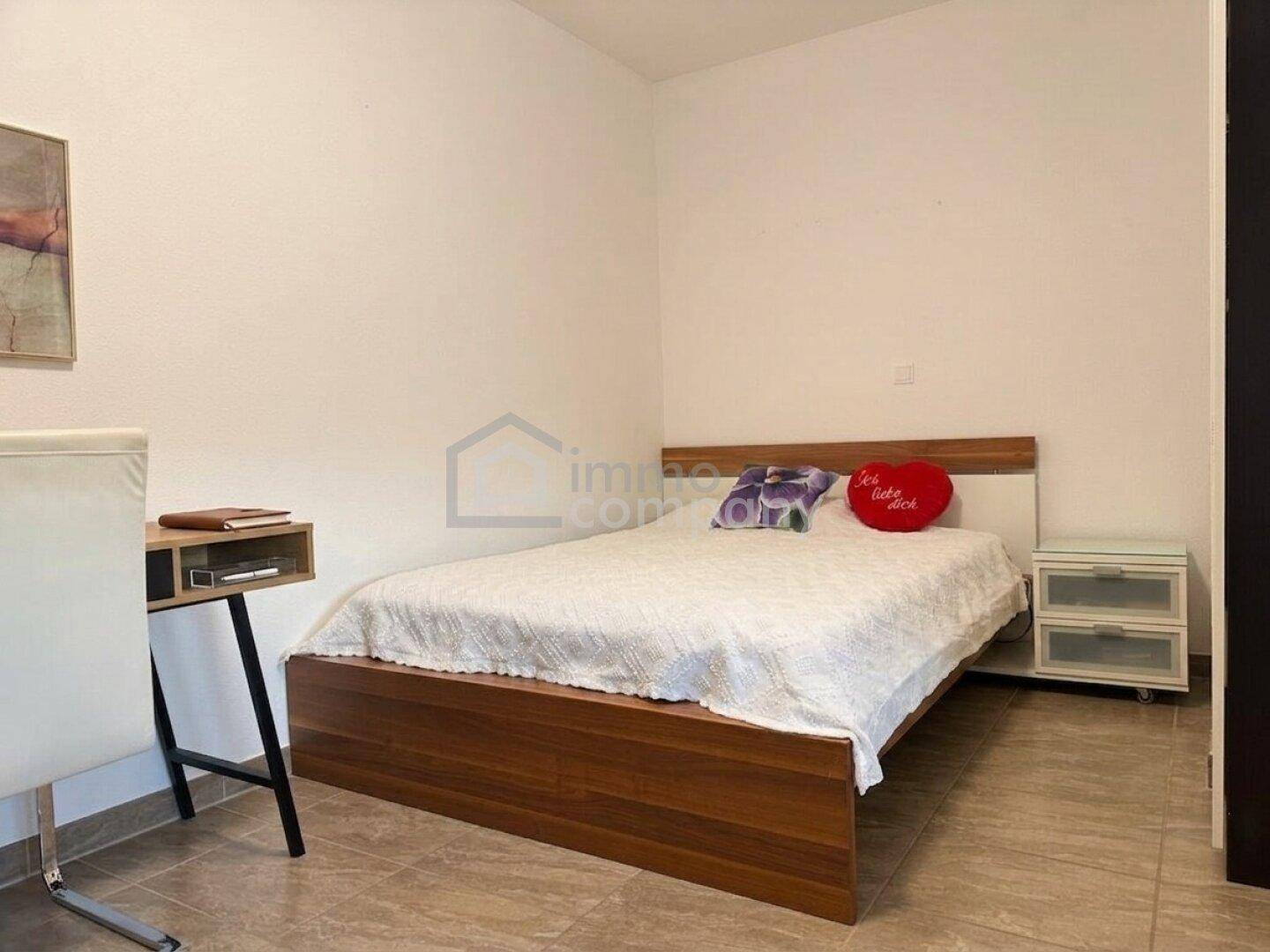 Schlafzimmer mit Einzelbett, Schreibtisch und Fliesenboden, ideal als Gäste- oder Kinderzimmer.