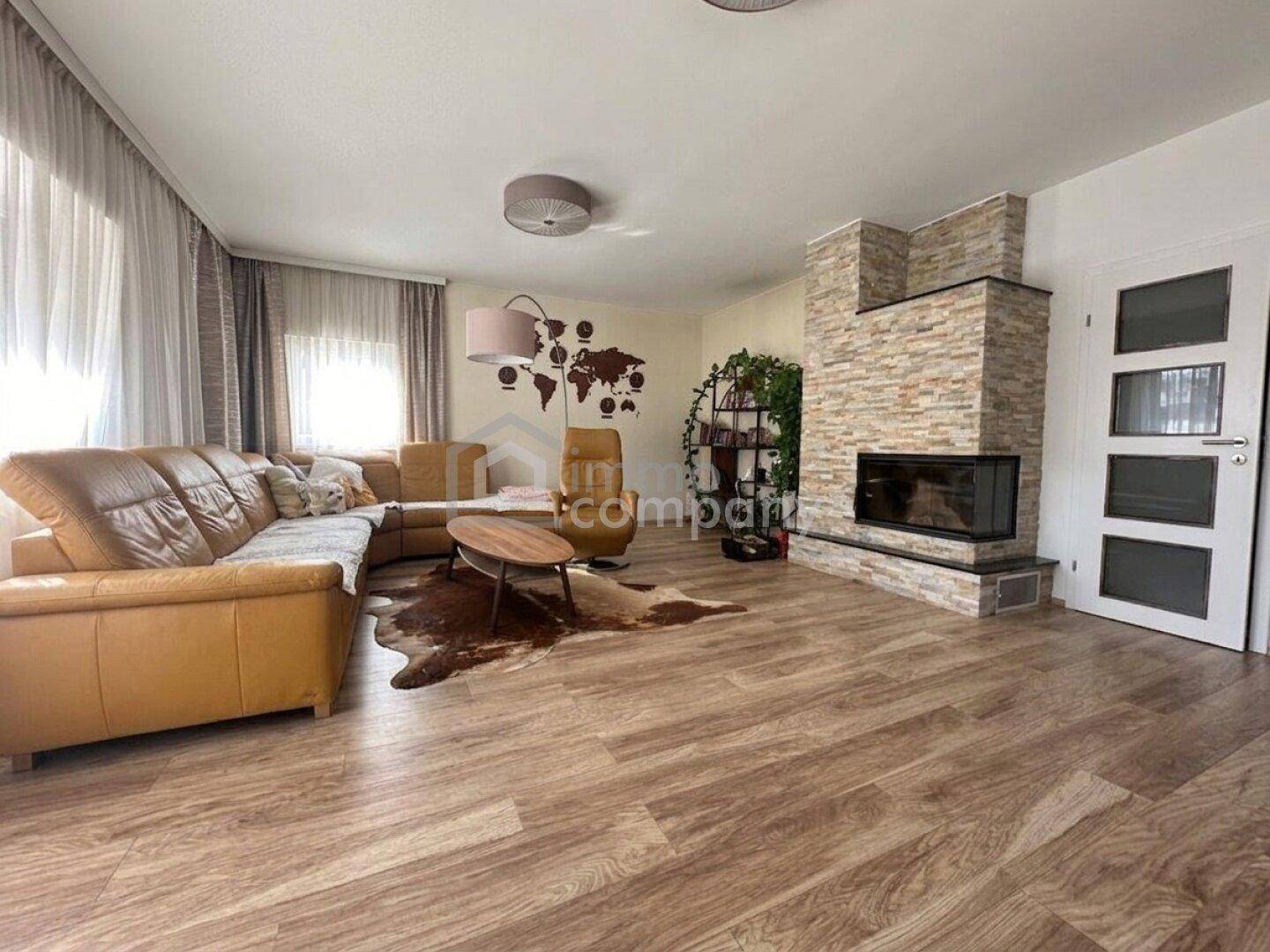 Gemütliches Wohnzimmer mit Ledersofas, modernem Kamin und hellem Holzfußboden.