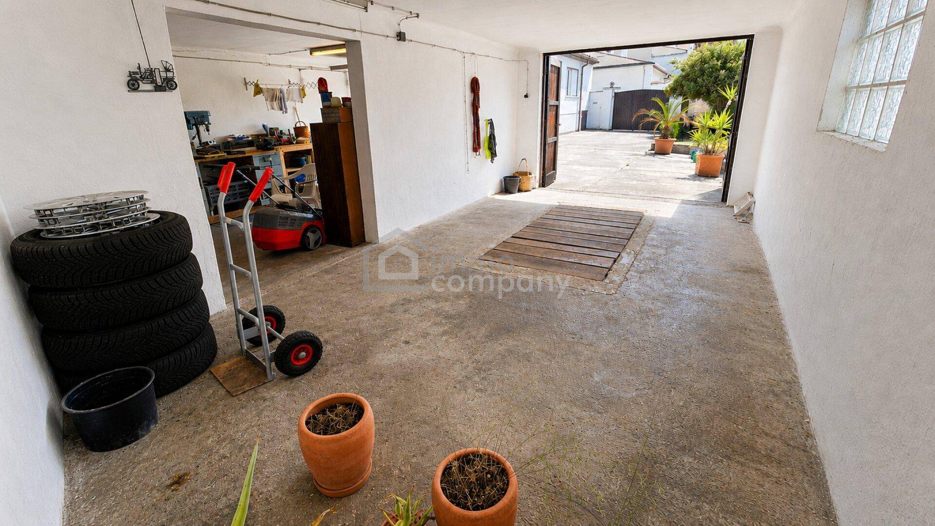Große Garage mit Zugang zum Außenbereich und viel Platz für Fahrzeuge und Werkstatt.