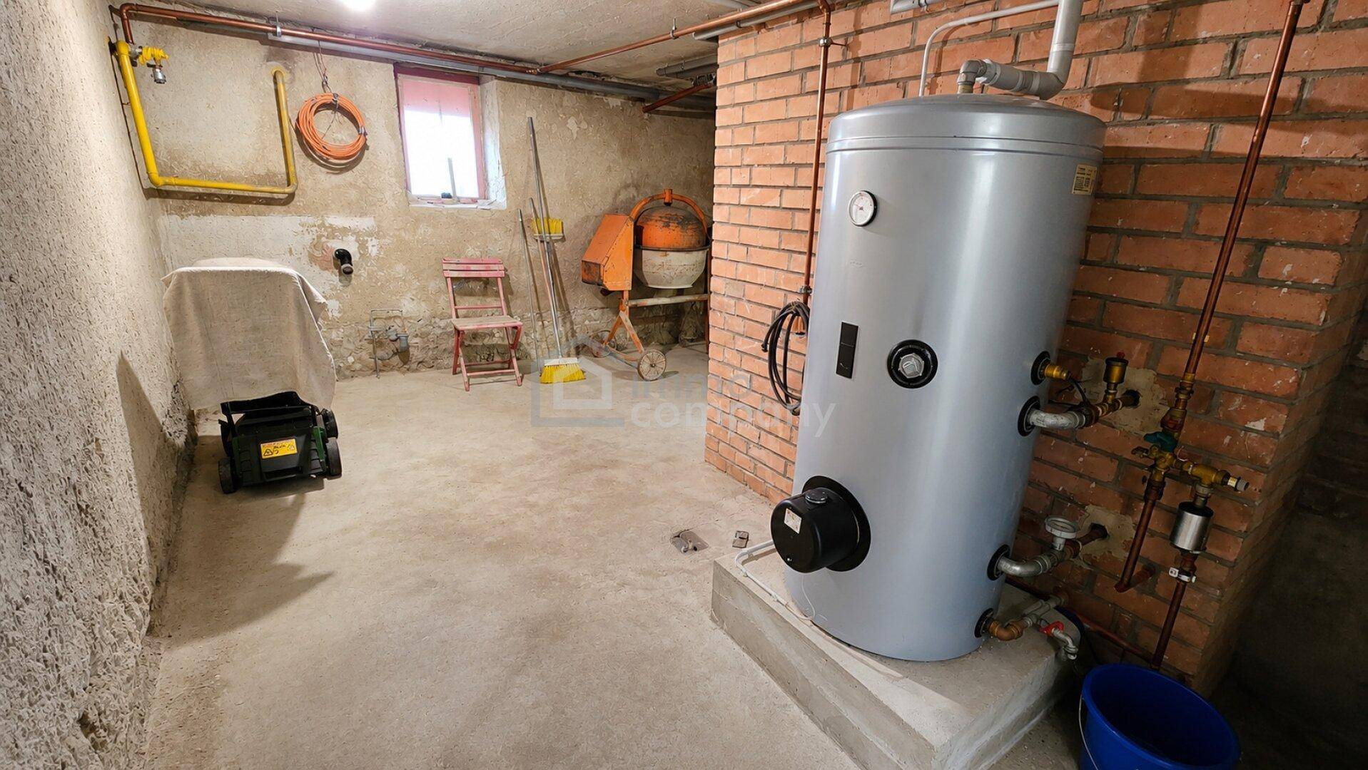 Kellerraum mit Warmwasserspeicher und Ziegelwänden, bietet zusätzlichen Stauraum.