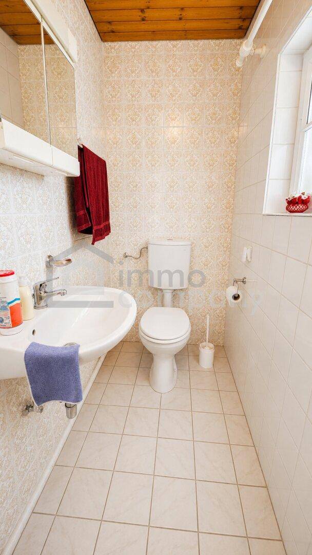 Helles Gäste-WC mit Fliesenboden, Waschbecken und Fenster.