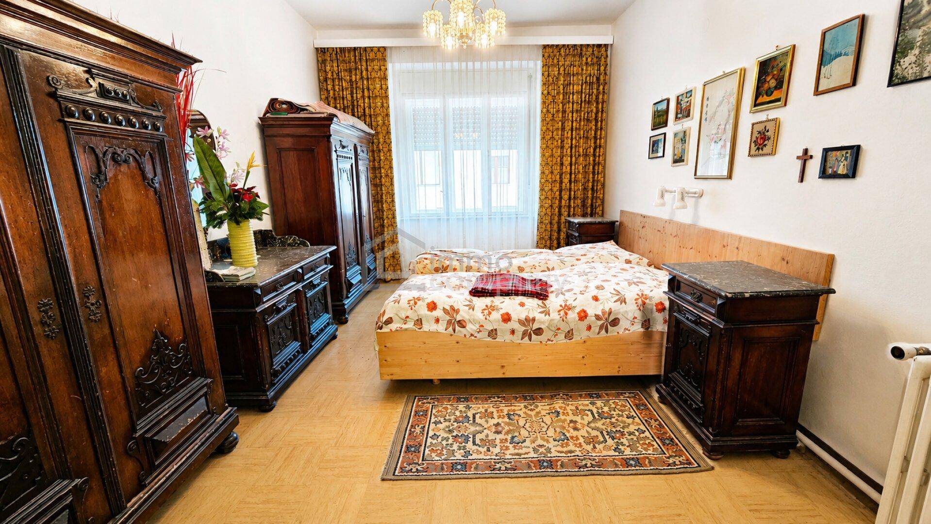 Schlafzimmer mit traditionellen Holzmöbeln, Teppichboden und hellem Fenster.