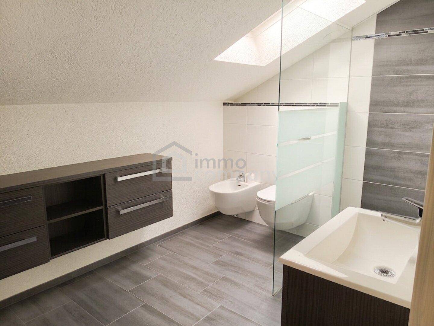 Dachgeschoss-Badezimmer mit Bidet, wandhängendem WC, Einzelwaschbecken und Dachfenster.