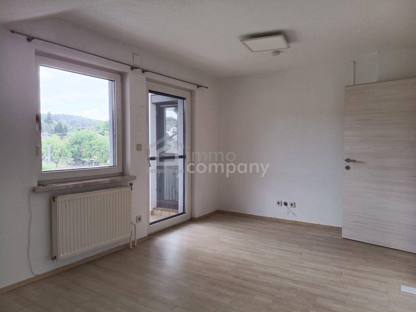 Schlafzimmer mit Laminatboden, großem Fenster und Zugang zu einem Balkon oder einer Terrasse.