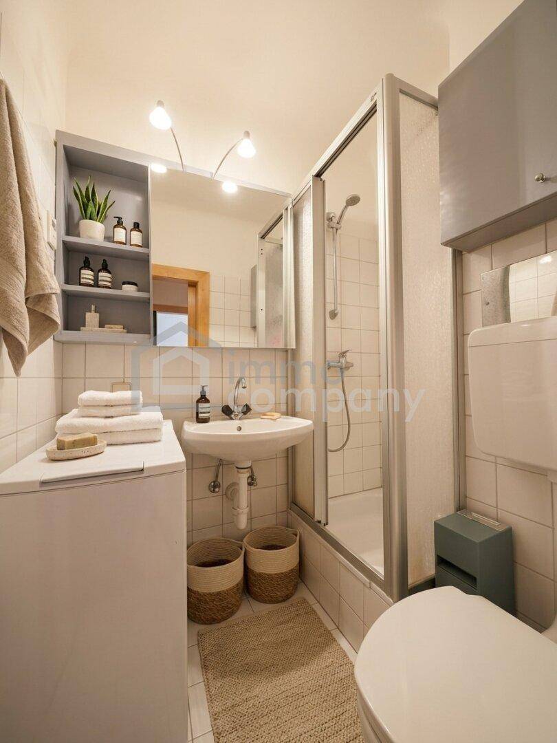 Funktionales Badezimmer mit Duschkabine, Waschbecken, Toilette und integrierter Waschmaschine.