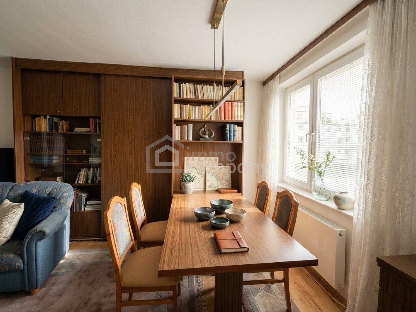 Heller Essbereich mit Holztisch, Stühlen und einem großen Fenster, umgeben von Bücherregalen.